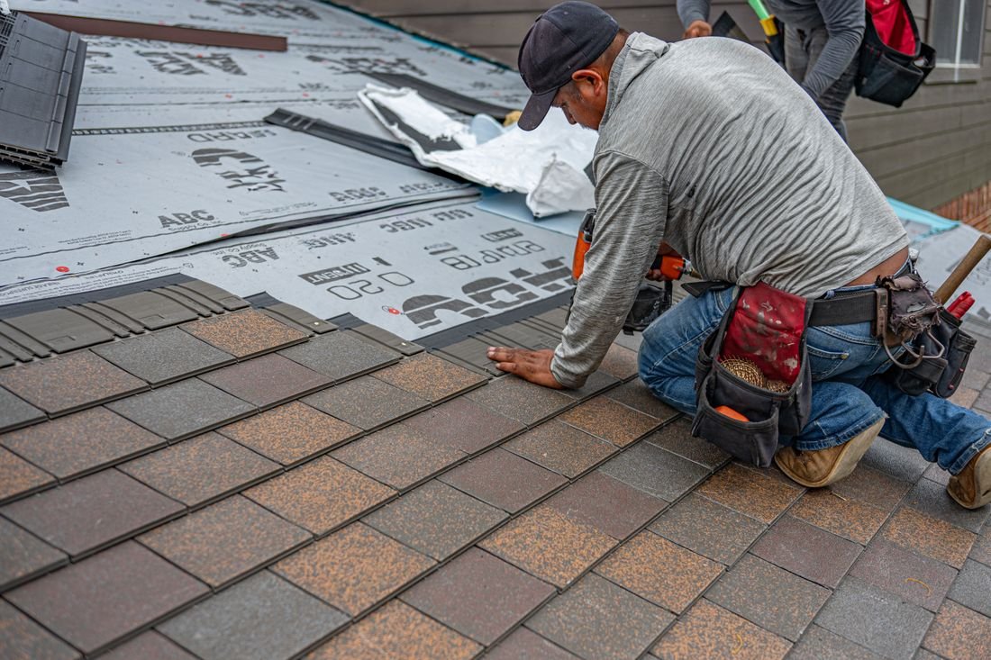 Roofer installing asphalt shingles on a residential roof